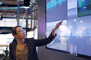 young information technologist (IT) conducting a seminar / lecture with the aid of a large screen.