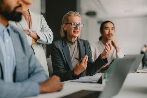 businesswoman with mba sitting at conference table with coworkers