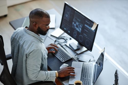 Man at desk considering between a MS in Computer Science vs a MS in Cybersecurity