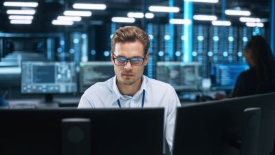 Man assessing AI Cybersecurity threats at a computer in a modern office